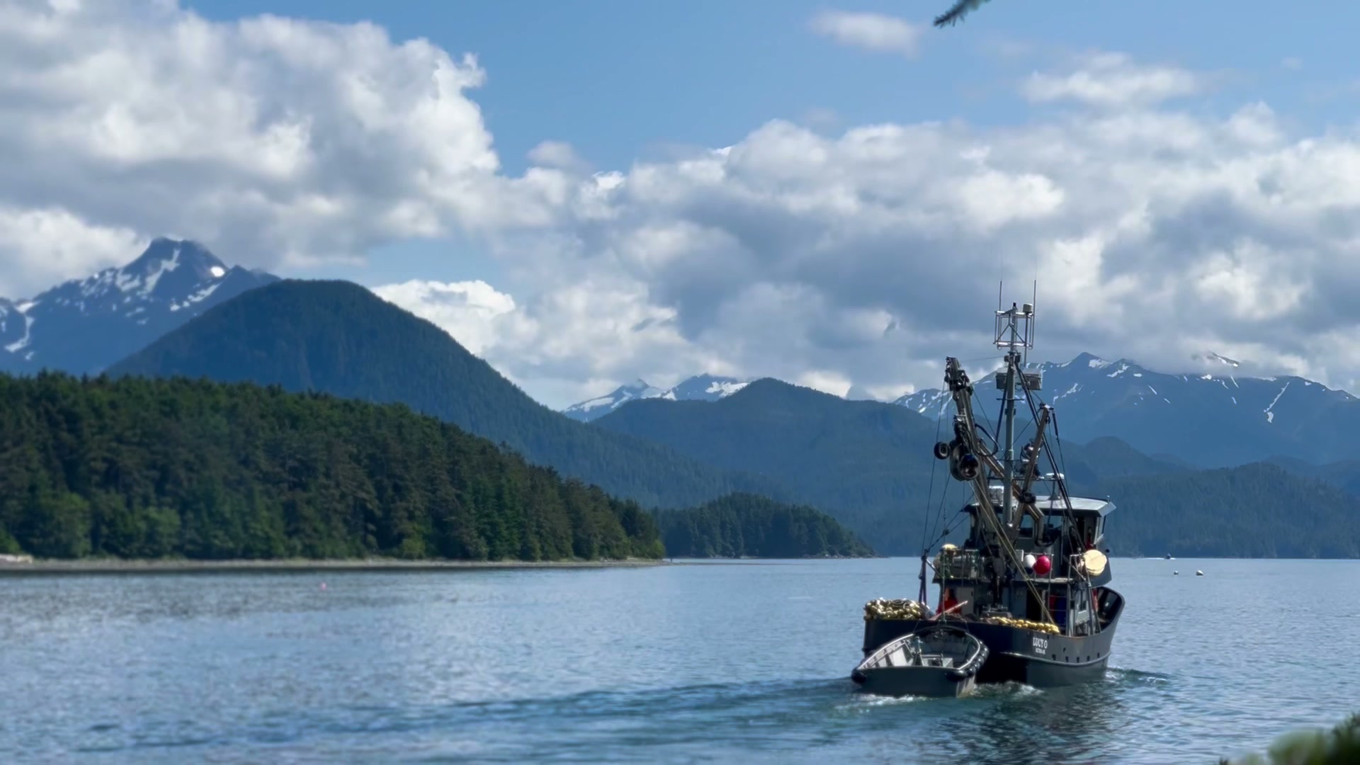 Salmon-hull fishing boat heading out of Sitka harbor toward snowcapped mountains